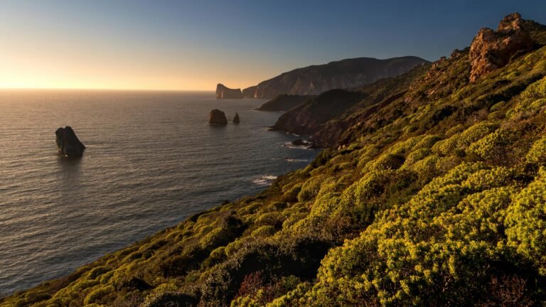 Stunning view of Sardinia's rocky coastline during sunset, showcasing rugged cliffs and serene ocean.
